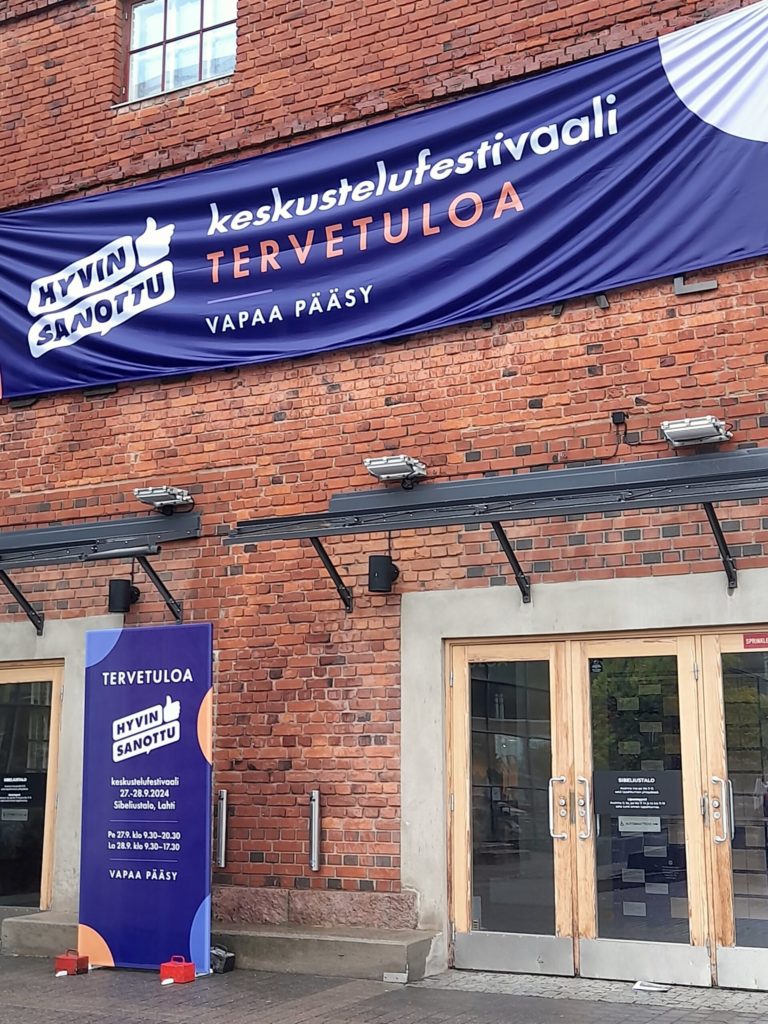 Kuva Lahden Sibeliustalon sisäänkäynnistä, jossa on Hyvin sanottu -keskustelufestivaalin banderolli.