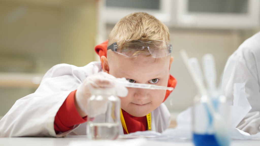 Valokuvassa lapsi työskentelee keskittyneesti pipetin kanssa.